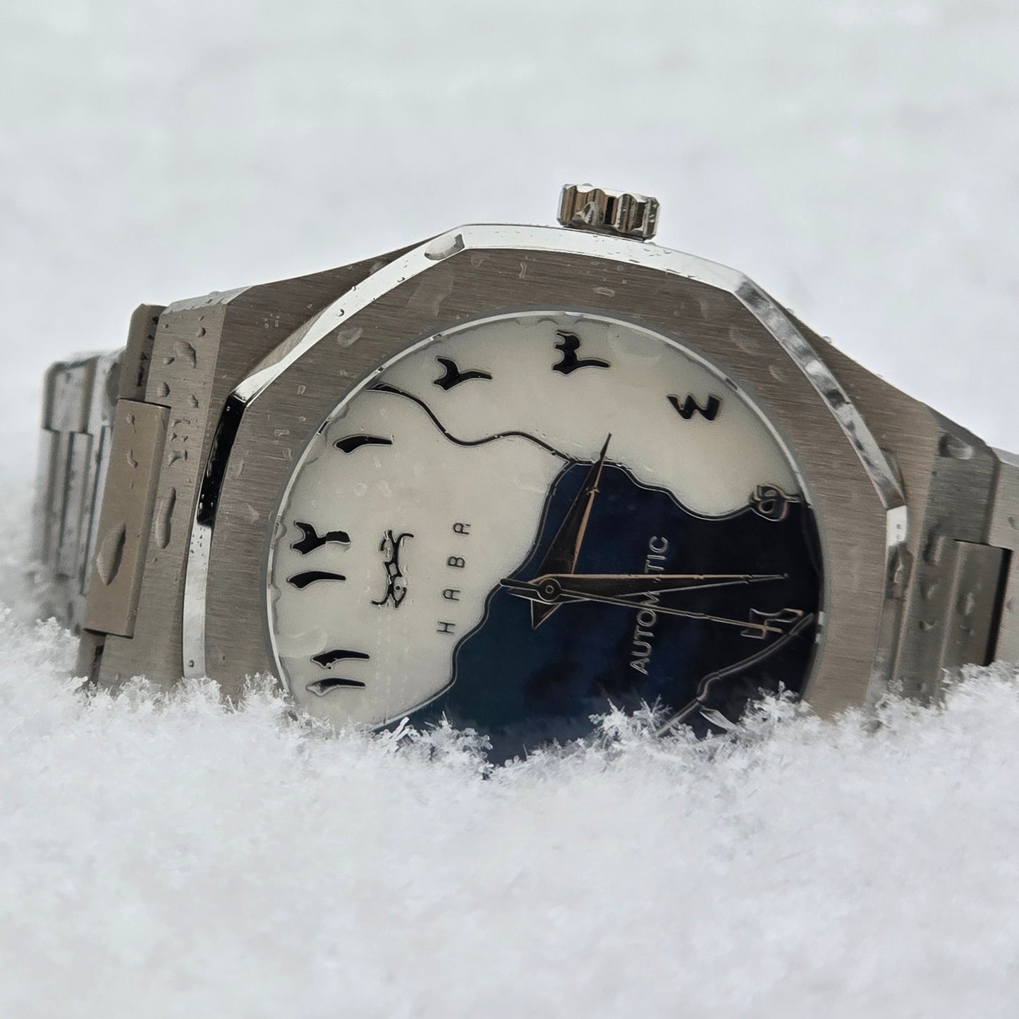 Montre automatique Arabic Dial pour homme avec chiffre arabe et cadran bleu vu de face et dans la neige.